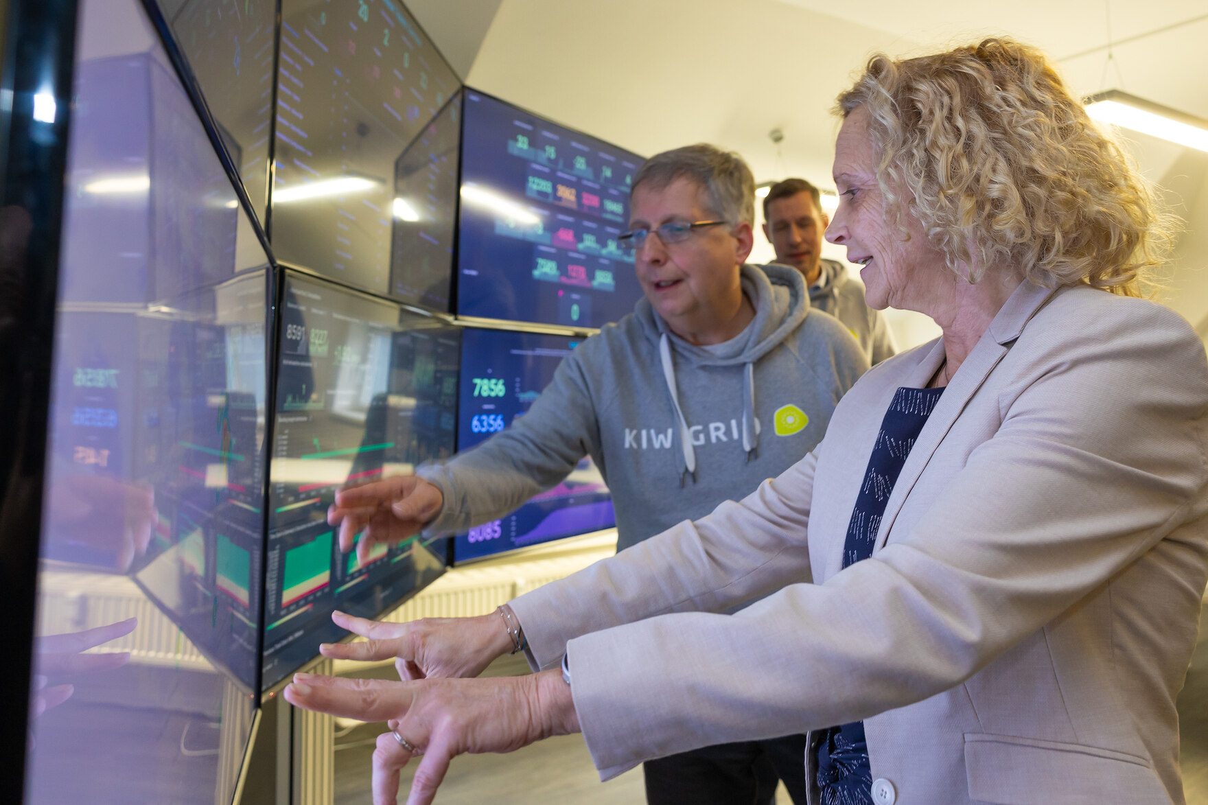 Staatssekretärin Ines Fröhlich steht neben einem Mann und zeigt auf einen Bildschirm.